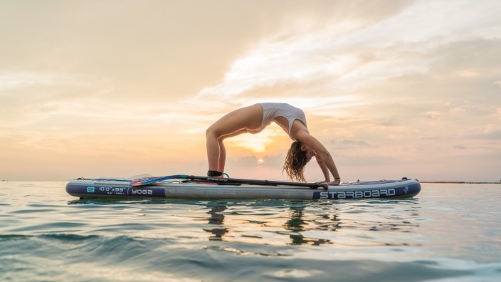 Freizeit: Yogaübungen auf dem Sup sind anstrengend, denn hier werden alle Muskelpartien trainiert. Wer die Balance auf dem kippeligen Board nicht halten kann, landet schnell im Wasser. Stimmungsvolle Kulisse für die Asanas auf dem Wasser sind die oberbayerischen Seen.