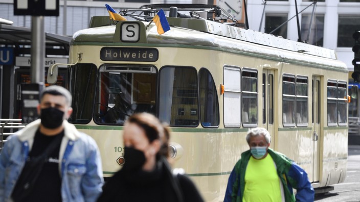 Corona in Deutschland: Menschen mit Masken vor einer Straßenbahn