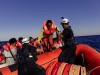 Mitarbeiter der Hilfsorganisation Sea Watch helfen Flüchtlingen an Bord eines sicheren Rettungsbootes.