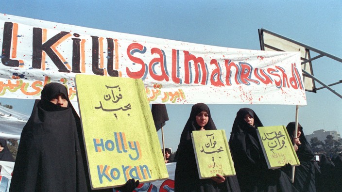 Attentat auf Salman Rushdie: Iranische Frauen in Teheran am 17. Februar 1989, drei Tage nach Chomeinis Fatwa gegen Rushdie, mit Bannern, auf denen "Heiliger Koran" und "Tötet Salman Rushdie" steht.