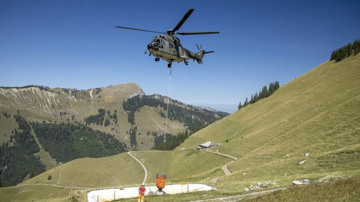 Schweiz: Ein Helikopter der Schweizer Armee versorgt Kühe mit Wasser.