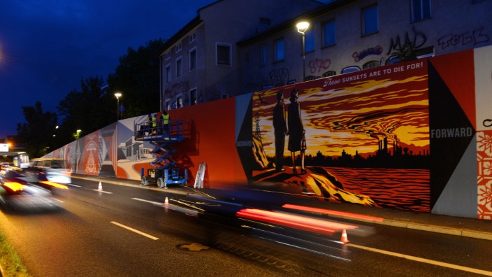 Straßenkunst: Gute 114 Meter lang ist das Street-Art-Werk, das Shepard Fairey mit Helfern entlang des Mittleren Rings in Sendling auf eine Mauer gemalt hat. Seine Kunst ist politisch, es geht um den Klimawandel, er will die Autofahrer, die im Stau stehen, wach rütteln.