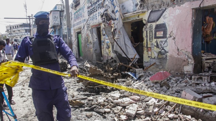 Somalia: Mogadischu: Ein Mitglied der Sicherheitskräfte sperrt die zerstörten Gebäude am Tatort ab.