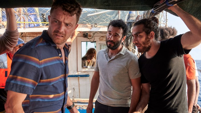 ZDF-Serie "Liberame": An Bord des Geflüchtetenbootes macht Jan Garbe (Friedrich Mücke, l.) eine schreckliche Entdeckung. Ismail Sabia (Mohamed Achour, M.) und Bilal Sabia (Tariq Al-Saies, r.) erklären ihm, dass der Motor ihres Bootes kaputt ist.