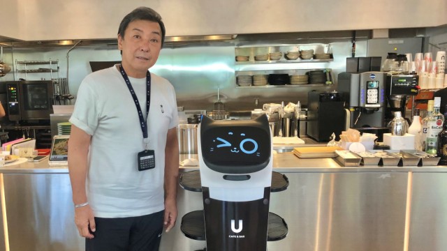 Urlaub in Japan: Chikao Watabe, Manager eines Speisecafés, mit einem Service-Roboter. In Japan sind die Menschen weiterhin sehr darauf bedacht, Abstand vom Virus zu halten.