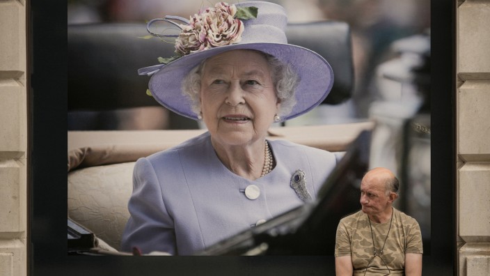 Großbritannien nach dem Tod der Queen: Im Zentrum Londons sitzt ein Mann vor einem Porträt Königin Elizabeths.