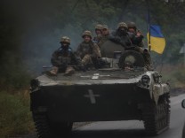 Ukrainian service members ride a BMP-1 infantry fighting vehicle near the town of Izium