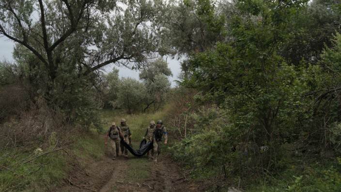 Ukraine: In einem zurückeroberten Gebiet bei Charkiw tragen ukrainische Soldaten einen Sack mit der Leiche eines getöteten Kameraden.