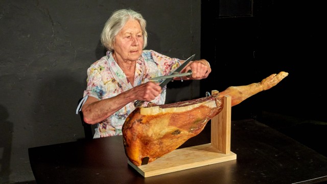 Senioren im Landkreis: Josefine Klein als alte Bäuerin wetzt die Messer und freut sich über den geschenkten Schinken.