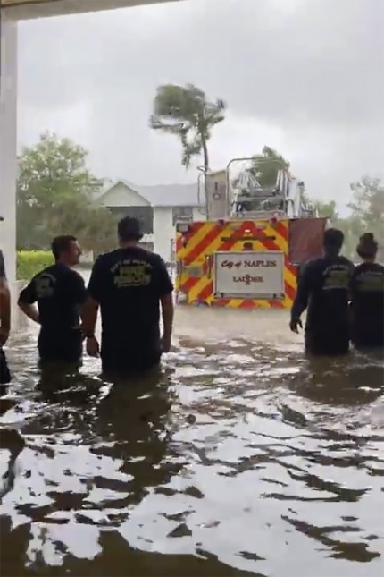 USA: In Naples blicken Feuerwehrleute auf ein Feuerwehrauto, das durch die Sturmflut des Hurrikans "Ian" im Wasser steht.