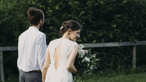 Rear view of bride and groom walking on meadow model released Symbolfoto PUBLICATIONxINxGERxSUIxAUT