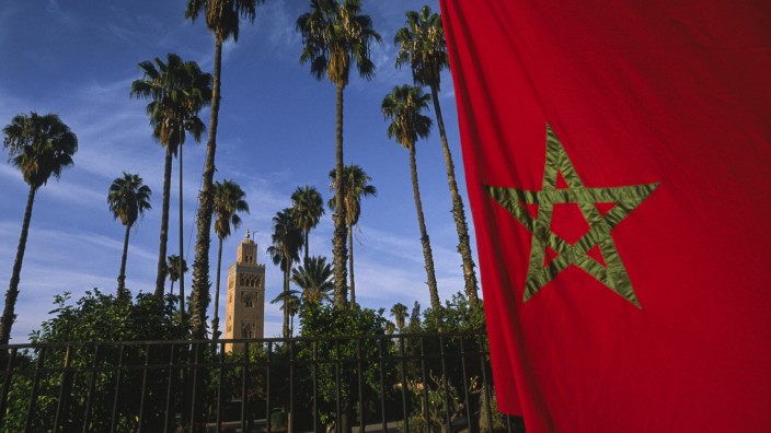 Mohamed Amjahid: "Let's Talk About Sex, Habibi": Sinnbild der Unterdrückung des Begehrens oder Ausdruck von Lebensfreude? Was einem näher liegt, könnte davon abhängen, wo man herkommt. Marokkanische Flagge und Blick durch den Lalla-Hasna-Park in Marrakesch und dem Minarett der Koutoubia-Moschee.