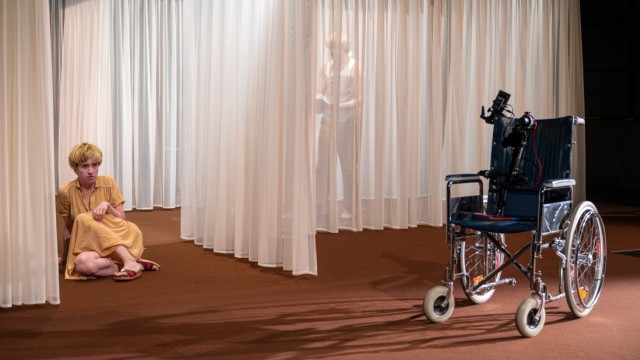 Uraufführung von Clemens J. Setz: Gardineneinblick in ein Gespensterhaus: Für Renate (Therese Dörr) existiert ihr Sohn im Rollstuhl weiter und kommuniziert mittels Kamera und Tablet.