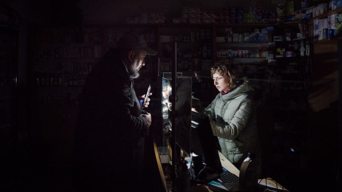 Welt-Aids-Tag: In einer Apotheke in Lwiw sorgt ein Kunde mit seinem Smartphone für ein wenig Licht. Die häufigen Stromausfälle sind für die Versorgung von Kranken katastrophal.