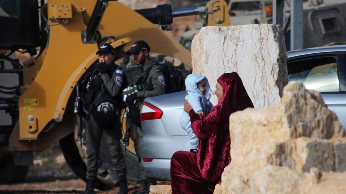 Nahostkonflikt: Eine Frau hält ein Baby, während Bagger der israelischen Armee Häuser im besetzten Westjordanland zerstören.