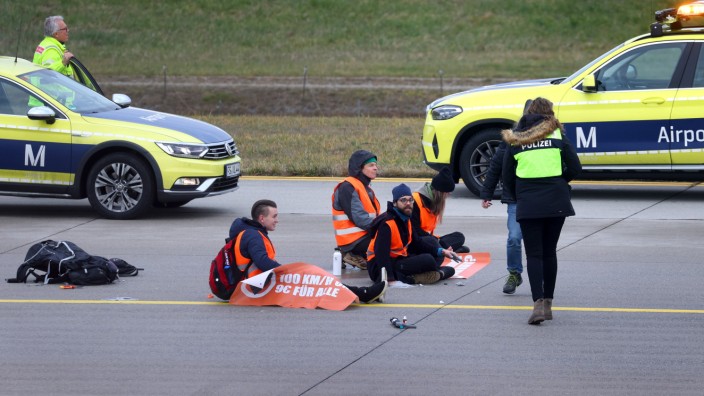 Protest der "Letzten Generation": Vier Klimaaktivisten sitzen mit angeklebten Händen auf dem Zubringer einer Start-und Landebahn am Airport Franz-Josef-Strauß.