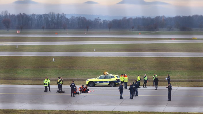 Blockade des Münchner Flughafens: Protestaktion Anfang Dezember: Vier Klimaaktivisten sitzen mit angeklebten Händen auf dem Zubringer einer Start-und Landebahn am Flughafen Franz-Josef-Strauß.