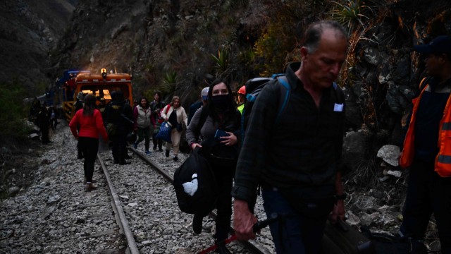 Government crisis in Peru: Tourists who had visited Machu Picchu walk along the train tracks to avoid the riots.