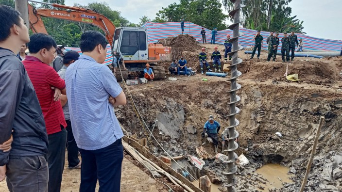 Vietnam: Helfer schauen auf die Baustelle, auf der ein zehnjähriger Junge in einem 35 Meter tiefen Rohr gefangen ist.