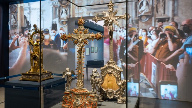 Ausstellung: Im Vordergrund die Kruzifixe, im Hintergrund Filmbilder der Prozession.