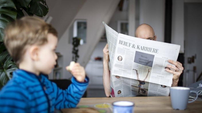 Familientrio: Leselust? Der Vater liest die Zeitung, das Kind schaut zu.