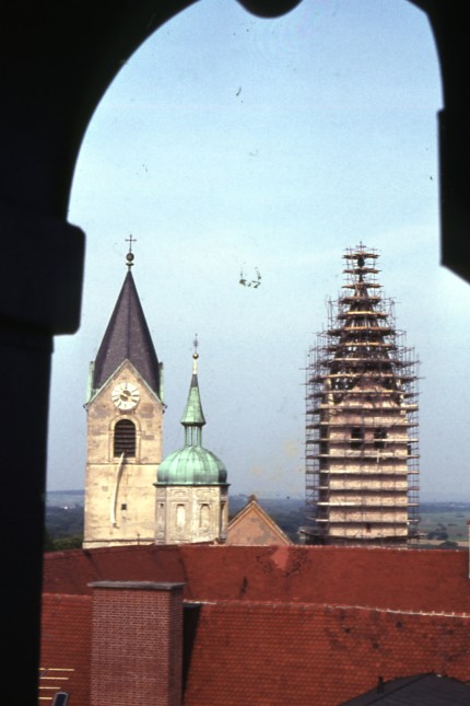 Archivstück des Monats: Diese Aufnahme zeigt die Domtürme von Westen im Jahr 1962. Die Neugestaltung des Südturms ist gerade in vollem Gange, der Nordturm ist noch unverändert. Zwischen den Domtürmen spitzt der 1965 abgebrochene Westgiebel hervor, im Vordergrund ist der kleine Residenzturm zu sehen. Fotograf Alois Lutzenberger stand in der Kuppellaterne des Süderkers des Klerikal-Seminars, dem so genannten "Seidl-Turm". Dieser wurde 2022 abgebrochen.