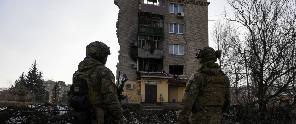 Ukrainian servicemen stand next to a residential building heavily damaged during a Russian military strike in Bakhmut
