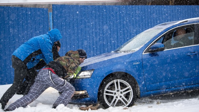 Wintereinbruch: Im tschechischen Frymburk schieben Menschen schieben ein Auto im Schneesturm.
