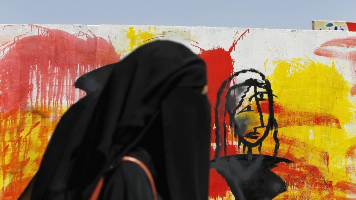 Frauen in Jemen: Bunt sind an dieser Straßenszene in Jemens Hauptstadt nur die Graffiti gegen den Bürgerkrieg.