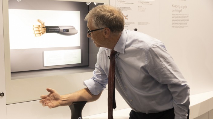 Während der Siko: Bill Gates probiert im Deutschen Museum eine Handprothese aus, die sich über die Armmuskeln steuern lässt.