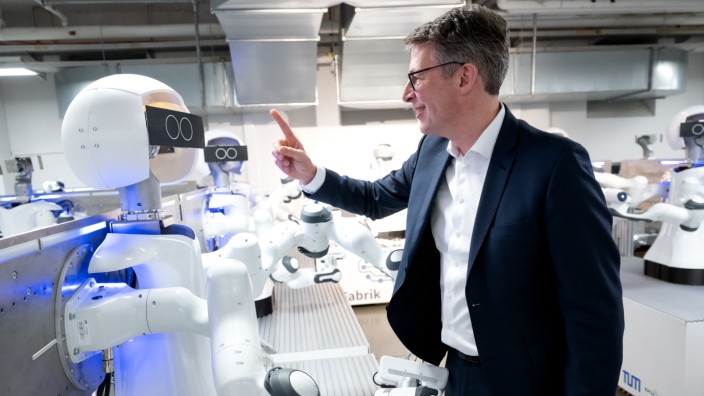 Schmuckbild: Gehen auf Tuchfühlung: Wissenschaftsminister Markus Blume (CSU) nähert sich einem Roboter.