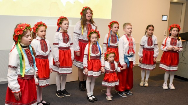 Veranstaltung für Ukrainer in Penzberg: Mit Blumenschmuck und ukrainischer Trachtenkleidung singt ein Kinderchor bei Roche in Penzberg Volkslieder über Freiheit und Stärke.