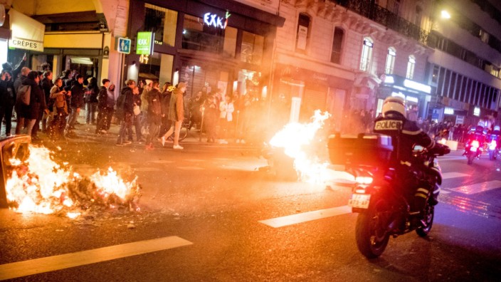 Rentenreform: Ein Feuer brennt auf einer Straße in Paris, während Menschen nach der Verabschiedung der umstrittenen Rentenreform protestieren.