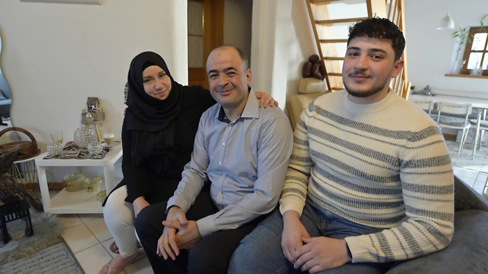 Serie "Meine zweite Heimat": Abdulmunaam Abdulhadi (Mitte), seine Frau Tahani und der ältere Sohn Mohamad sitzen auf einem vom Vater gepolsterten Sofa in ihrer Wohnung in Neubiberg.