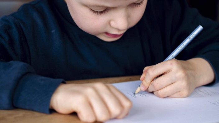 Weitere Briefe: Ein fünfjähriger Junge sitzt zu Hause und schreibt mit der linken Hand.