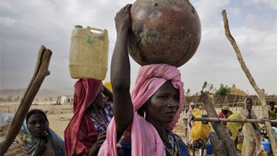 Völkermord in Darfur: Flüchtlinge aus Darfur, die Schutz in Camps im Osten des Tschad suchen, müssen mühsam das Wasser zu den Hütten transportieren.