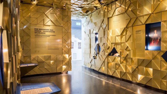 Bayreuth: Die Ausstellung im Bayreuther Museum mit Welterbe-Informationszentrum liefert Informationen zur Markgräfin Wilhelmine von Preußen in einer goldfarbigen Wandinstallation.