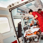 paramedic taking care of a woman in the ambulance with broken arm;  Ambulance service emergency doctor interview magazine