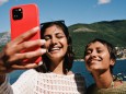 Woman taking selfie with female friend on smart phone; foto