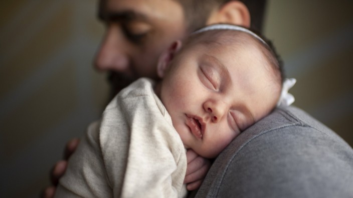 Typisch deutsch: Ein neugeborenes Baby schläft auf der Schulter des Vaters (Symbolfoto).