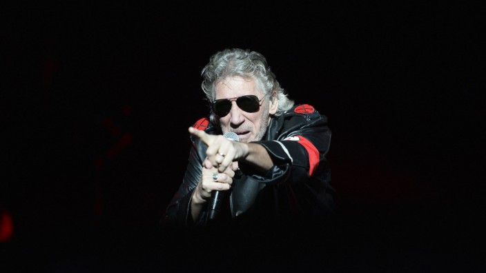 Ermittlungen gegen Roger Waters: Hier könnte eine Straftat vorliegen: Roger Waters im Ledermantel mit roter Armbinde, hier bei einem Konzert 2013. Bei seiner aktuellen Tournee hat er außerdem mit einer Sturmgewehr-Attrappe in die Menge geschossen.