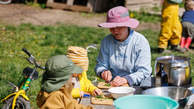 Kindererziehung: Die Kindergartenleiterin des Bauernhof-Kindergartens Giebelstadt, Elke Kleider, bereitet zusammen mit zwei Kindern im Freien die Suppe für das Mittagessen vor.