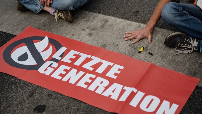 "Letzte Generation": Ein Aktivist der Klimaschützergruppe "Letzte Generation", der seine Hand auf der Straße festgeklebt hat, blockiert eine Kreuzung in Göttingen.