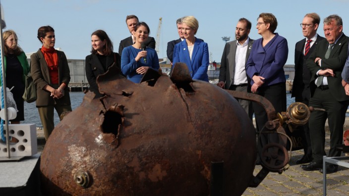 Ostseerat: Bundesaußenministerin Baerbock erklärt am Mikrofon im Hafen von Wismar die Funktionsweise einer Wassermine aus dem Ersten Weltkrieg.