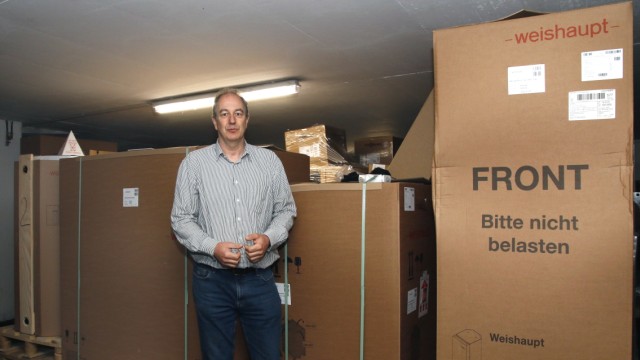 Energiewende: Bernd Krüger im Lager mit noch verpackten Teilen einer Heizungsanlage bestehend aus Wärmepumpe, Wasserspeicher und Wärmetauscher.