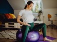 Young pregnant woman doing relaxation exercises with a pilates ball at home
