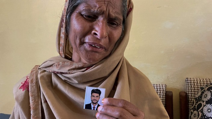 Nach dem Bootsunglück im Mittelmeer: Trauer um die Vermissten: Tazeem Pervaiz aus dem Dorf Bandli im pakistanischen Teil von Kaschmir mit dem Foto ihres Sohnes Taquir Pervaiz, der an Bord des gesunkenen Schiffs war.