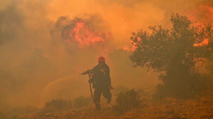 Extreme Temperaturen: Griechenland, 19. Juli 2023: Ein Feuerwehrmann versucht, einen Waldbrand in der Nähe der Hauptstadt Athen unter Kontrolle zu bringen.