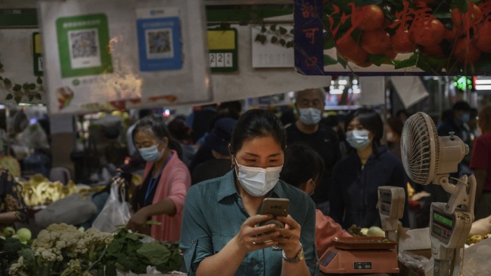 Ein-App-Strategie: Eine Handy-Nutzerin in Peking - im Hintergrund ein QR-Code der Firma Wechat, die selbst auf lokalen Märkten wie diesem als Zahlungsdienstleister auftritt.