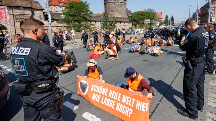Klima-Proteste: Aktivisten der "Letzten Generation" protestieren am Donnerstag mit einem Banner mit der Aufschrift "Schöne heile Welt hier - wie lange noch?" bei einer Straßenblockade vor dem Nürnberger Hauptbahnhof.